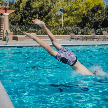 Person diving into a swimming pool, capturing summer fun and leisure outdoors.